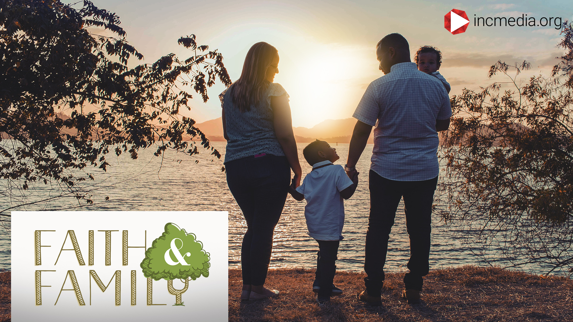 father and mother holding hands with their 2 kids in front of the water