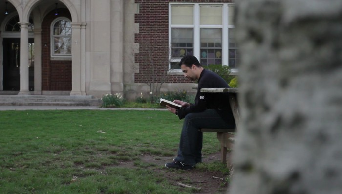 man sitting on bench reading a book