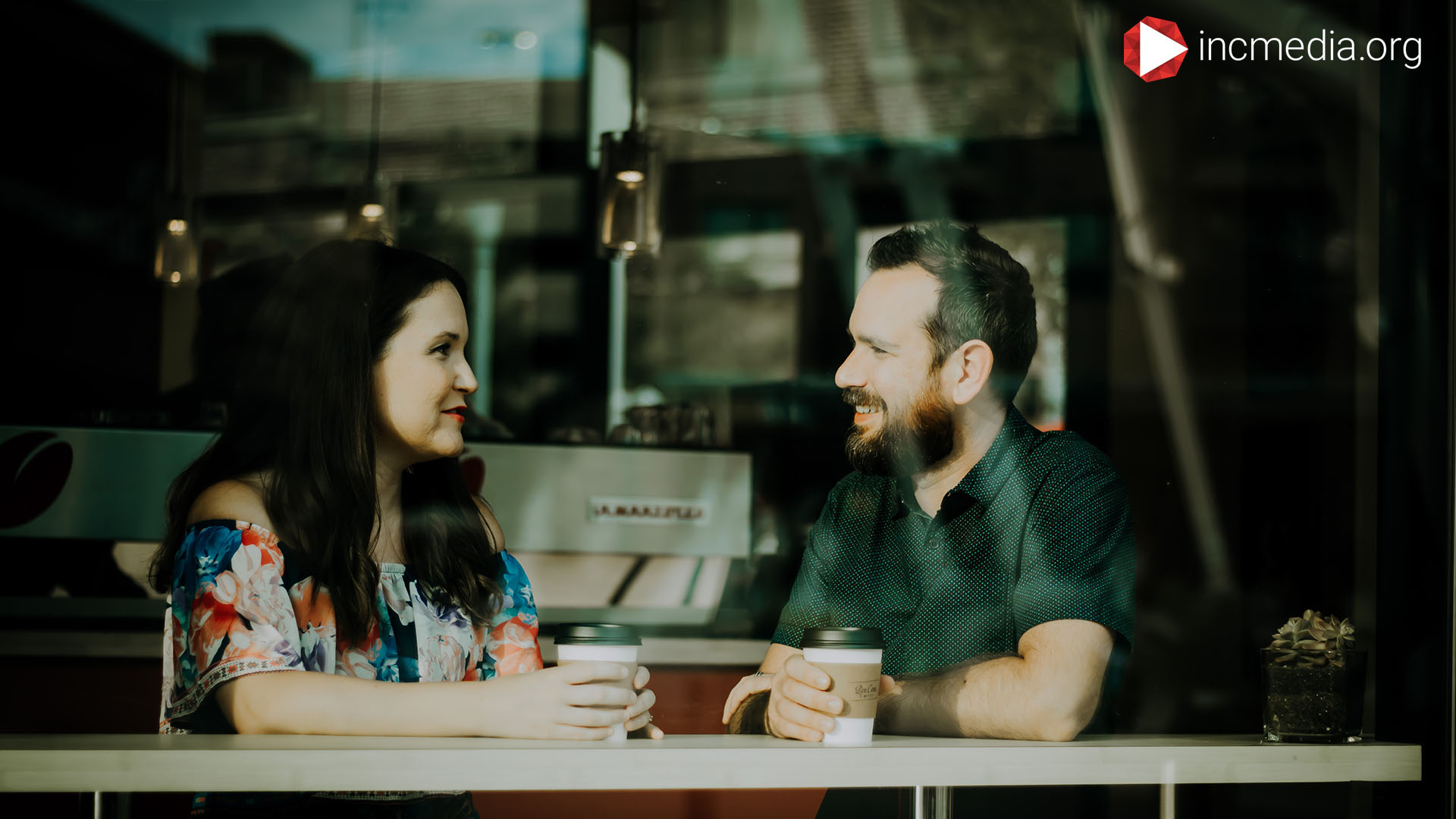 Man and wife looking at each talking over coffee.